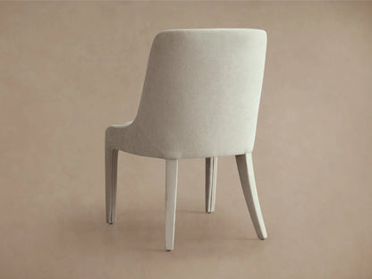 Burns Dining Chair in beige with elegant, fully upholstered frame, rounded backrest, and dense foam seat on a wooden floor.