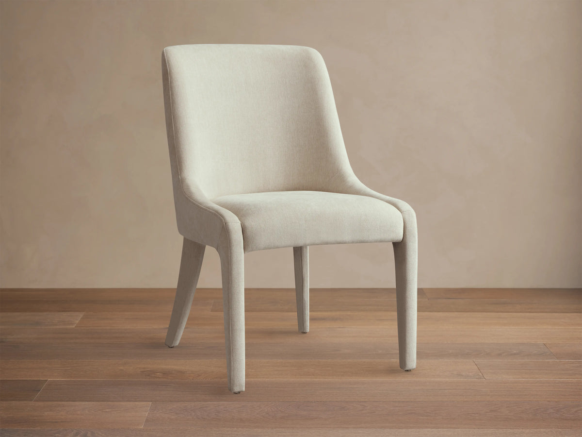 Burns Dining Chair in light beige fabric with elegantly rounded backrest, viewed from the back angle, on a neutral background.