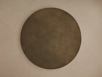 Close-up of round recycled brass-toned metal tabletop with a visible hammered texture and subtle sheen on a light background.