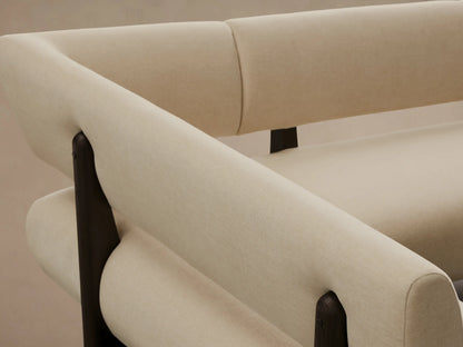 L-shaped Beau Banquette, cream upholstered sectional with a dark exposed wood frame and legs, on a wooden floor.