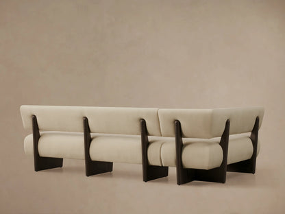 Angled close-up of Beau Banquette: light beige upholstered seat and backrest cushions with dark wood exposed frame.