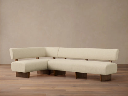 Beau Banquette: L-shaped cream bouclv© sofa with dark wood frame, legs, and back supports, on a wooden floor.