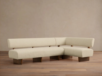 Beau Banquette, L-shaped, cream textured upholstery on a dark wood frame, angled on a wood floor against a light wall.