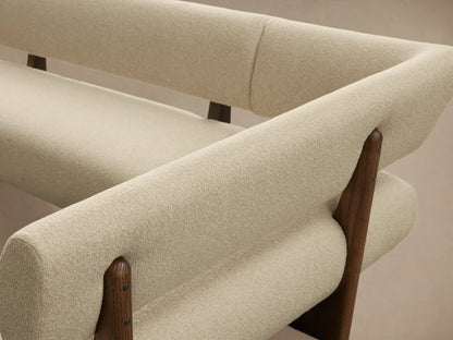 L-shaped Beau Banquette with cream boucle upholstery and dark wood frame, angled on a wooden floor.