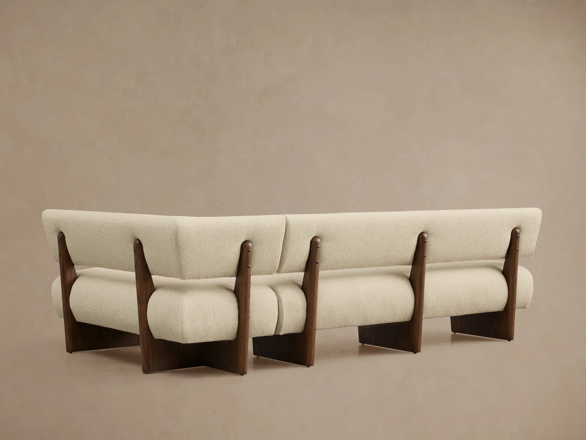 Angled close-up of a Beau Banquette, featuring creamy textured fabric upholstery and exposed dark wood frame details.