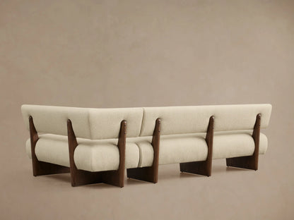 Angled close-up of a Beau Banquette, featuring creamy textured fabric upholstery and exposed dark wood frame details.