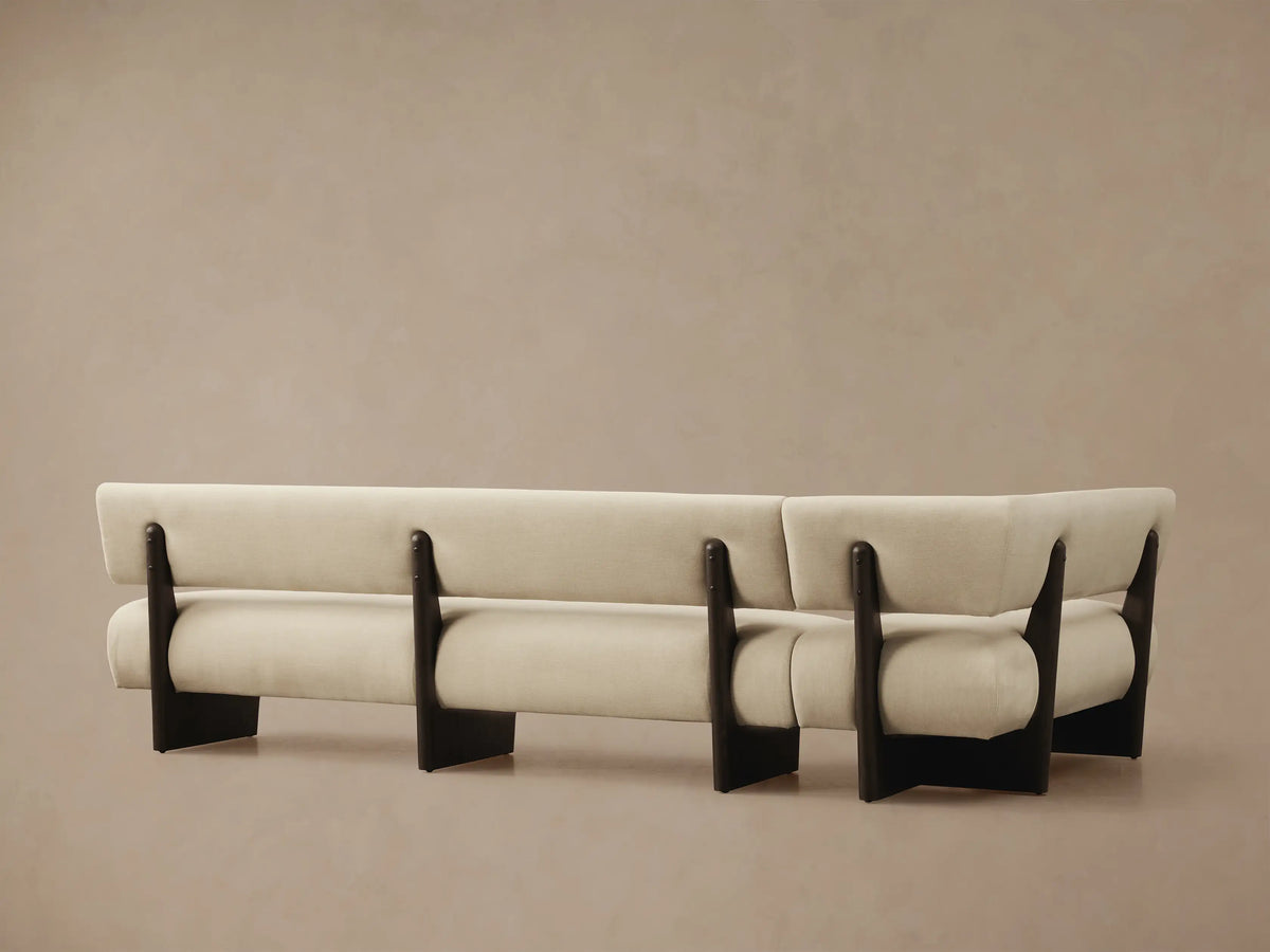 Beau Banquette close-up, showing light beige textured upholstery on the back and arm, with a dark exposed wood frame detail.
