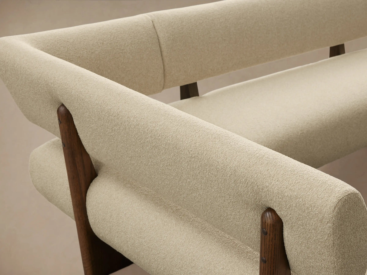 Beau Banquette: Modern L-shaped banquette with light cream textured upholstery, supported by a dark wood frame. Viewed on wood floor.