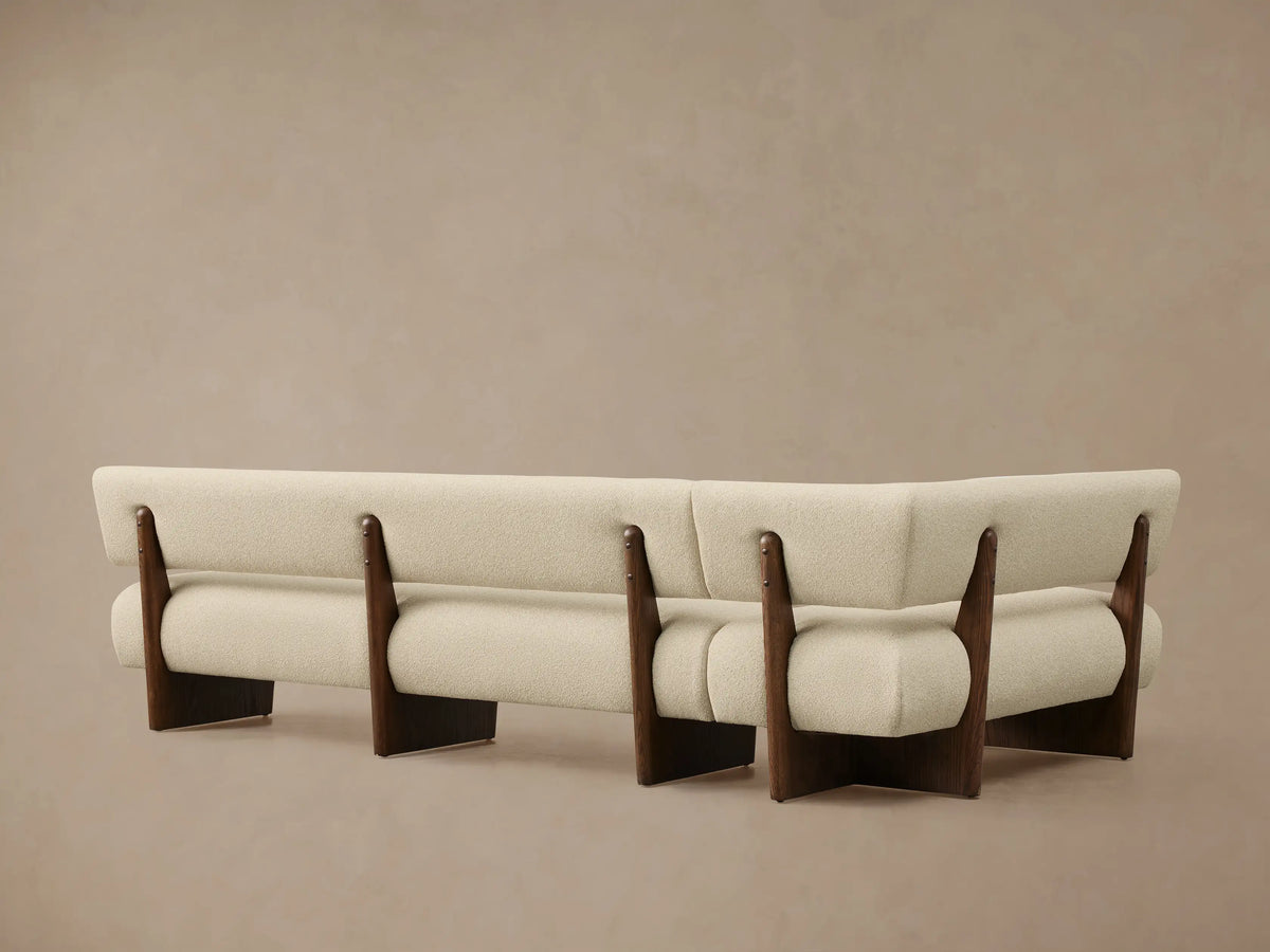 Beau Banquette corner section with textured cream upholstery, supported by a dark wood frame, viewed from a close, elevated angle.