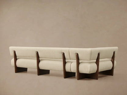 Beau Banquette corner section with textured cream upholstery, supported by a dark wood frame, viewed from a close, elevated angle.