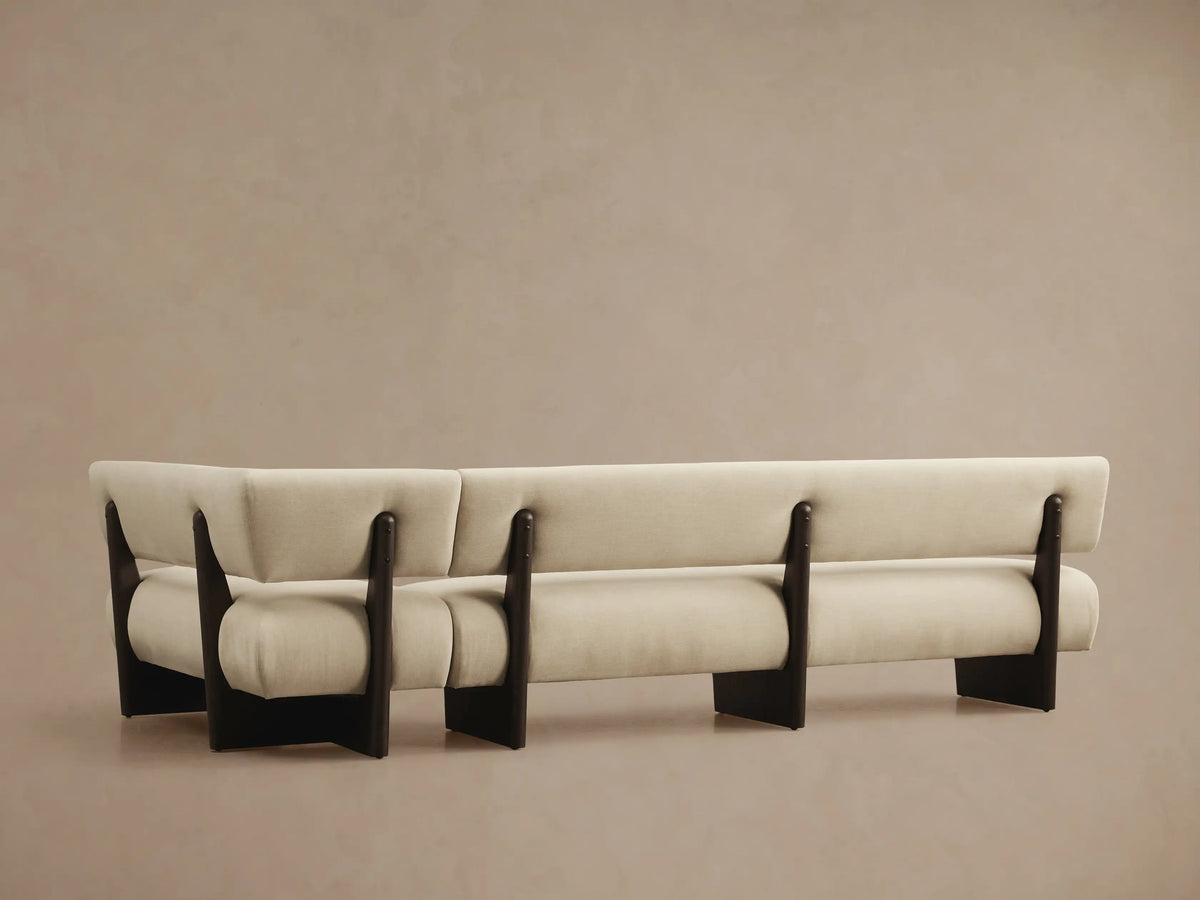 Close-up angled view of a light beige Beau Banquette with dark exposed wood frame details, showing upholstery texture.