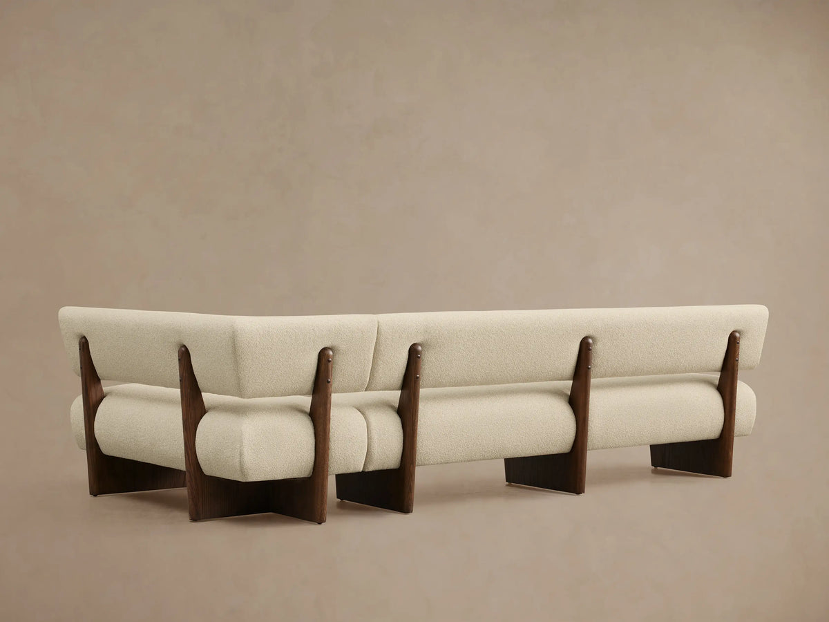 Beau Banquette, close-up, with cream textured fabric upholstery and dark wood frame details, showcasing curved modern design.