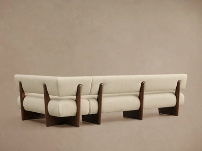 Beau Banquette, close-up, with cream textured fabric upholstery and dark wood frame details, showcasing curved modern design.