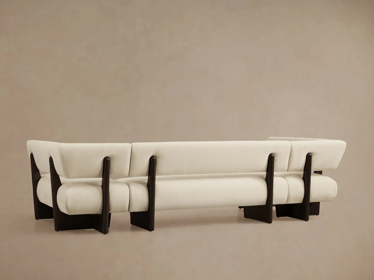 Beau U-Shaped Banquette corner, angled. Cream textured fabric upholstery with rounded cushions and dark wood frame details.