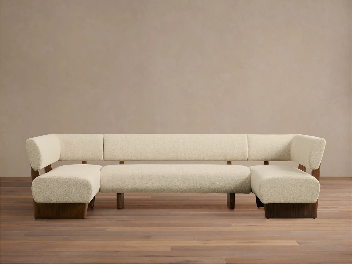 Beau U-Shaped Banquette. Cream textured upholstery, dark wood frame & base. Front view on wood floor.