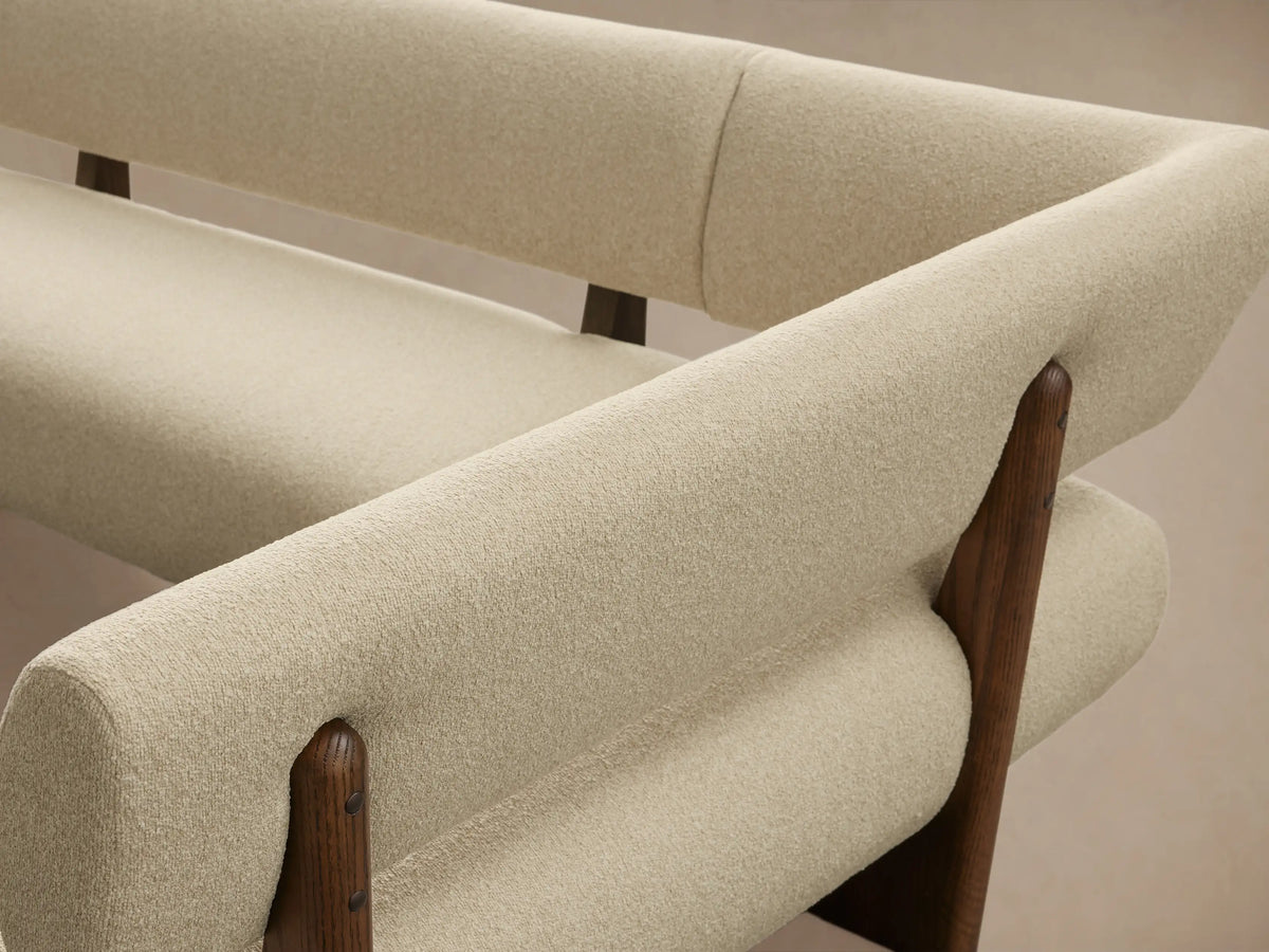 Beau U-Shaped Banquette, cream boucle upholstery with dark wood frames, on a light wooden floor against a beige wall.