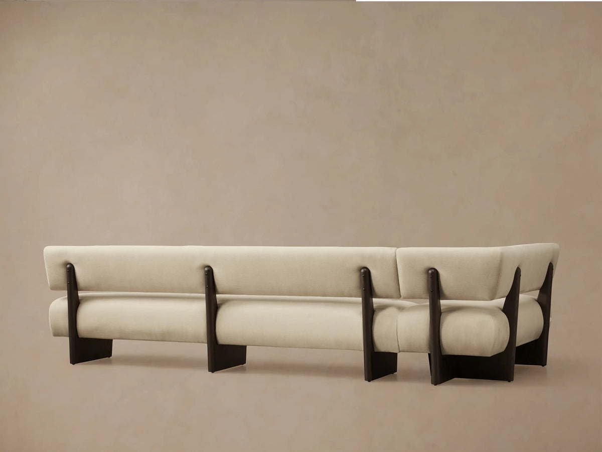 Angled close-up of Beau Banquette showing light beige fabric armrest curving over a dark wooden support, with seat & back.