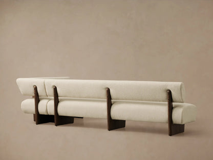 Beau Banquette, a creamy, textured fabric corner bench with dark oak veneer frame and exposed wood details.