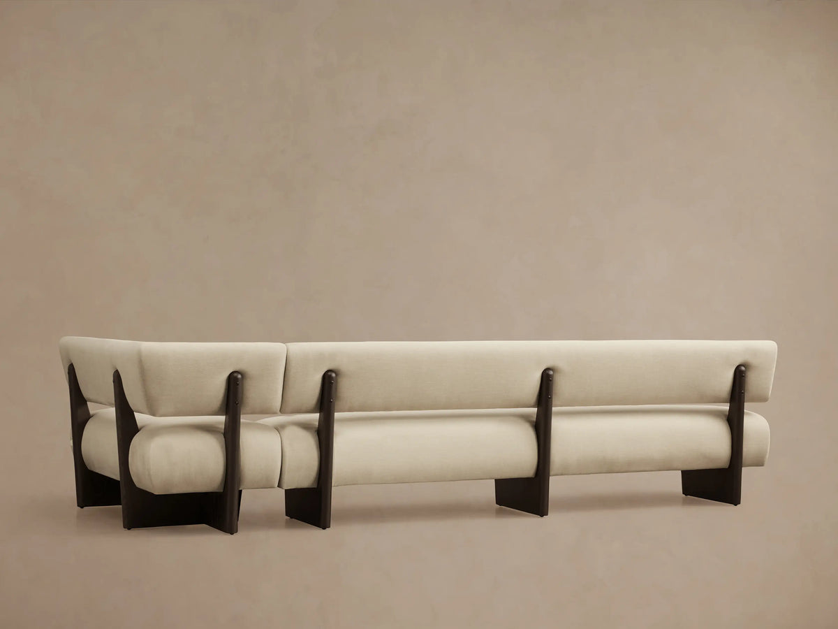 Close-up of Beau Banquette. Cream-colored upholstered curved back and armrest, with dark wooden supports.