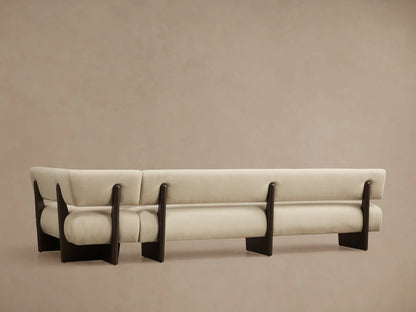 Close-up of Beau Banquette. Cream-colored upholstered curved back and armrest, with dark wooden supports.