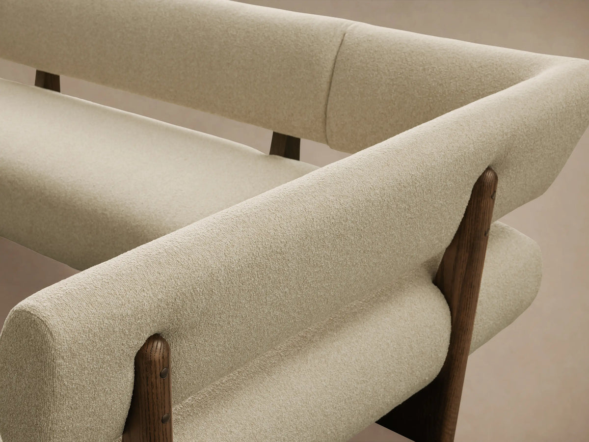 Beau Banquette: L-shaped sofa with textured cream cushions and dark wood base, angled on a wooden floor.