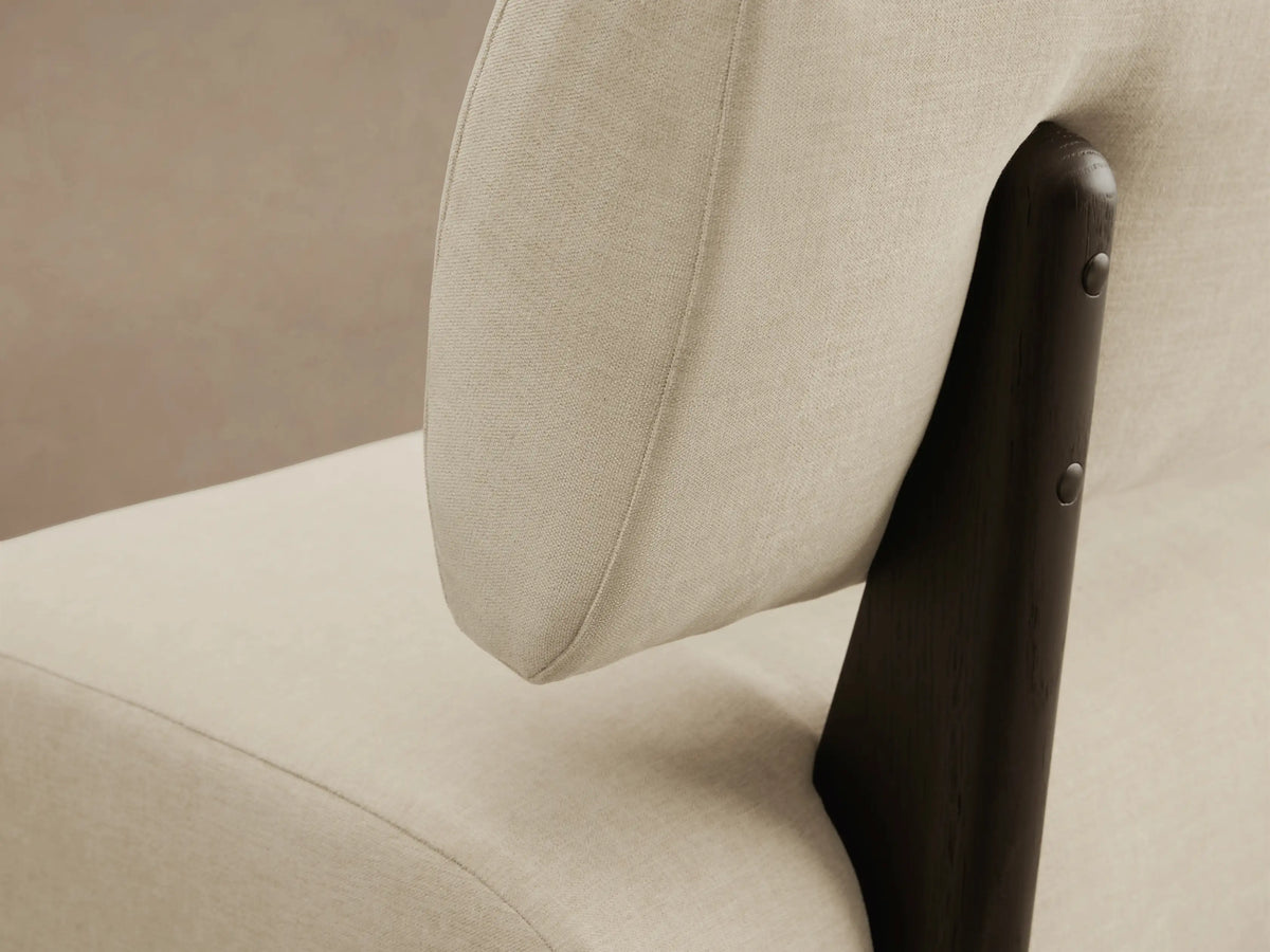 Beau Banquette: Long, modern cream upholstered bench with a rounded backrest, supported by dark, flat legs on wood floor.