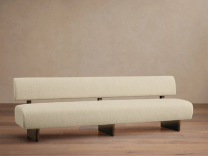 Beau Banquette, cream boucl?? fabric, minimalist design with separated backrest, dark wood legs on a wooden floor.