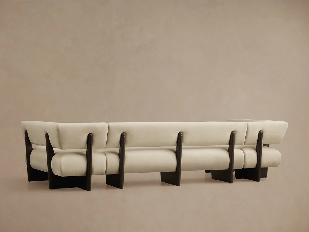 Close-up of Beau U-Shaped Banquette corner. Light beige fabric upholstery with dark brown exposed wood frame.
