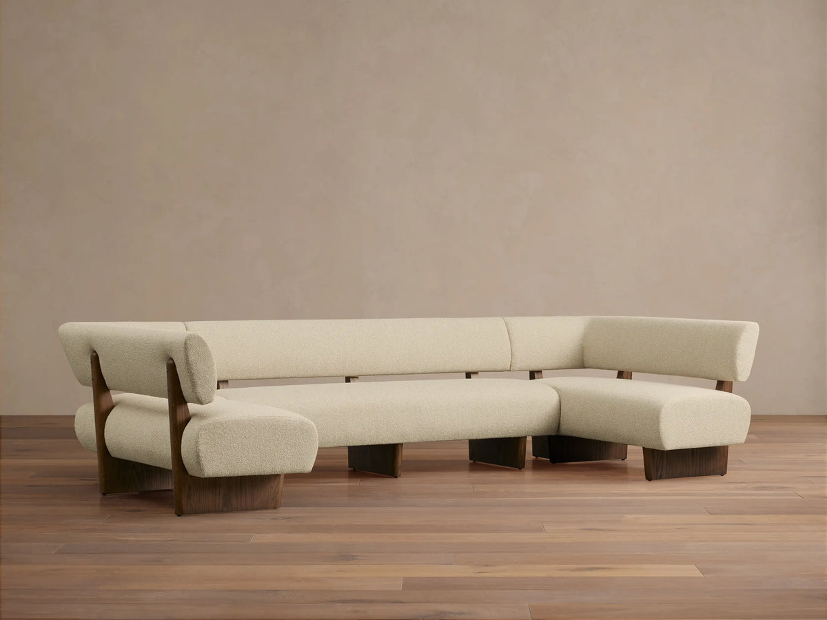 Beau U-Shaped Banquette: Light cream boucle U-shaped sofa with dark wood frame, front view, against a neutral wall.