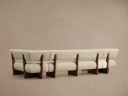 Angled close-up of Beau U-Shaped Banquette. Light cream textured upholstery on curved arm and back, with dark wood frame.