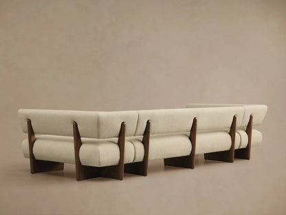 Angled view of a Beau U-Shaped Banquette, featuring light cream textured fabric upholstery and dark wood supports.
