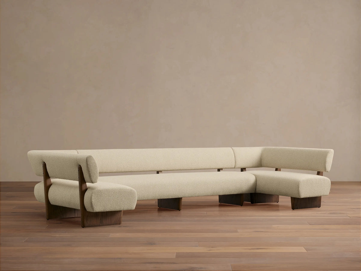 Beau U-Shaped Banquette with light cream upholstery, dark oak wood frame, sitting on a hardwood floor.
