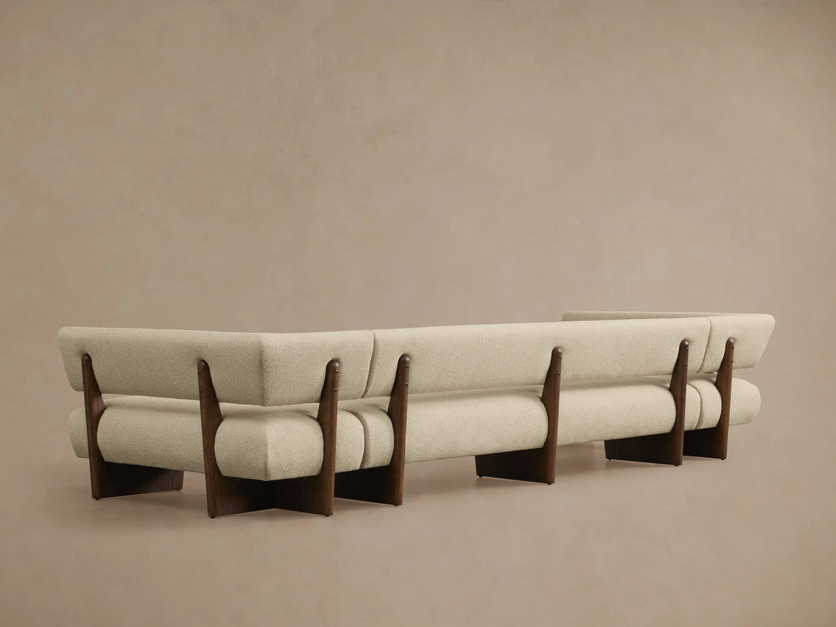 Beau U-Shaped Banquette. Close-up of light beige textured fabric and dark wood frame, showing a curved section and plush upholstery.