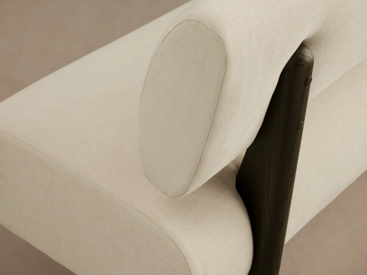 Beau Banquette: Modern cream upholstered banquette with dark supports and a separate backrest, on a wooden floor.
