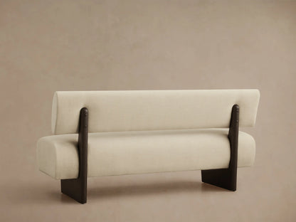 Close-up of Beau Banquette, showing its cream fabric upholstery and a dark brown wooden armrest from a top-down angle.