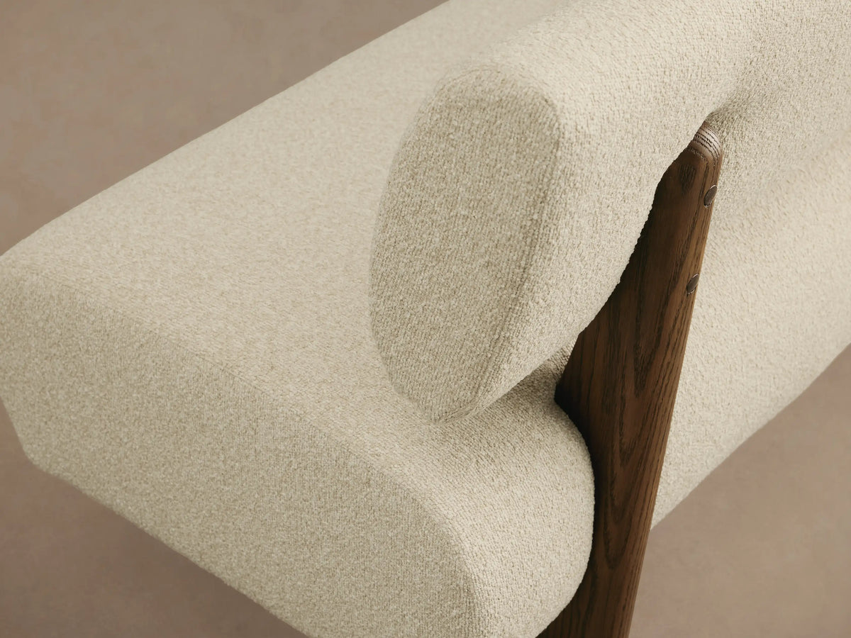Beau Banquette: modern cream boucle banquette with a rounded backrest, separate from the seat, supported by dark wood legs.