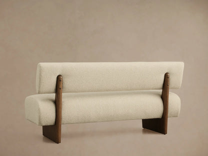 High-angle view of a Beau Banquette upholstered in light beige textured fabric with a dark wooden frame and curved backrest.