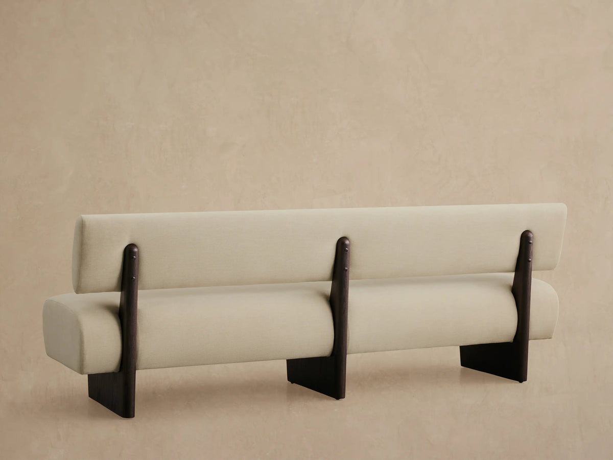 Close-up of Beau Banquette's light beige upholstered backrest and seat, with dark brown wooden support, viewed from above.