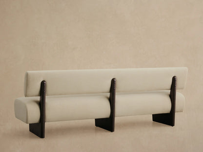 Close-up of Beau Banquette's light beige upholstered backrest and seat, with dark brown wooden support, viewed from above.