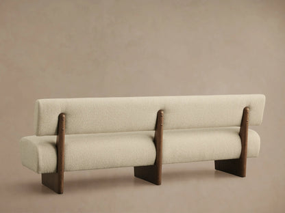 Close-up of Beau Banquette's textured light cream boucl?? fabric seat and rounded back, with a visible dark wood frame.