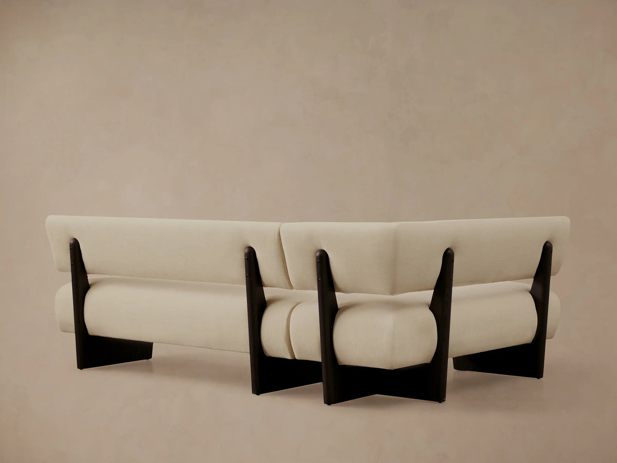 Close-up of Beau Banquette's cream upholstery and dark wood frame, showing the armrest and back at an angle.