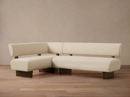 L-shaped Beau Banquette in cream boucle fabric with dark wooden base and frame, on a wood floor against a neutral wall.