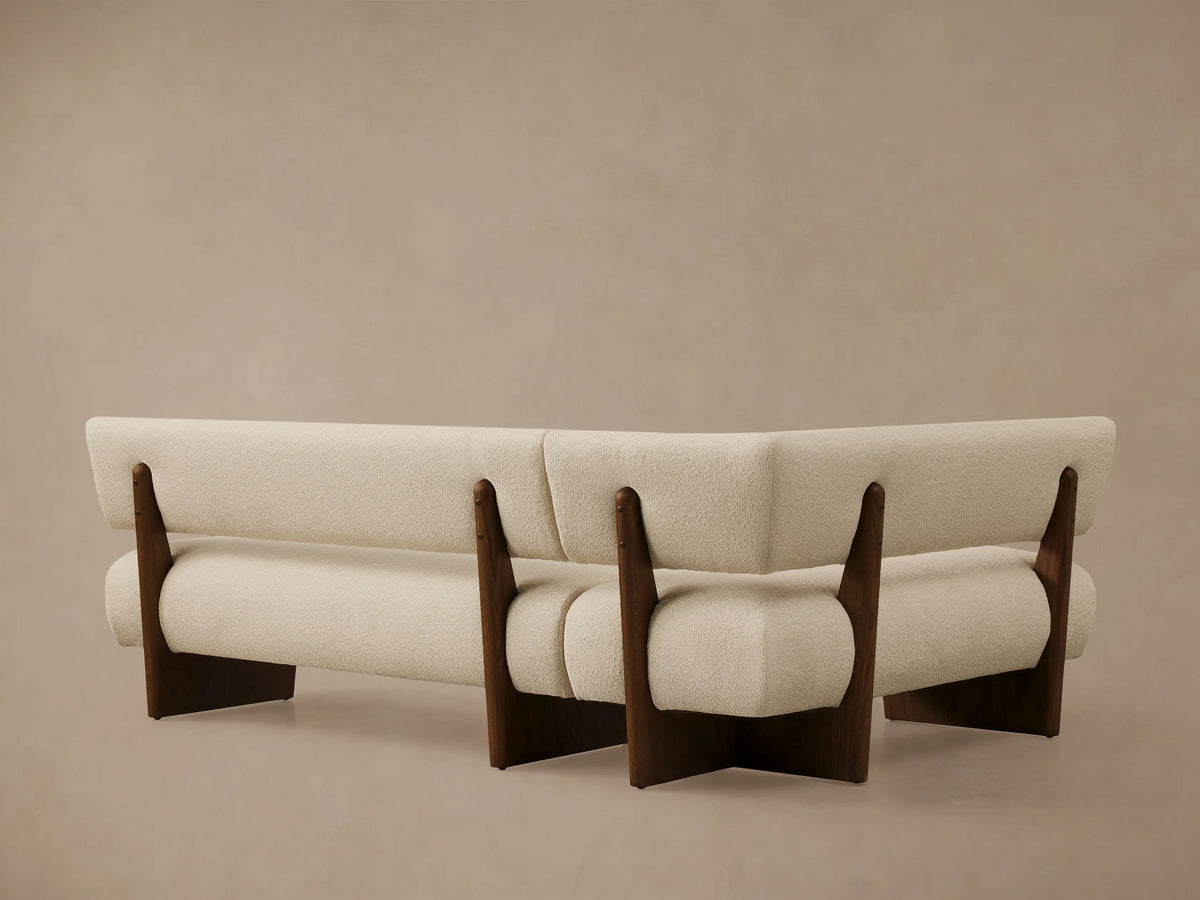 Beau Banquette corner in cream boucle upholstery, with a dark oak wood frame visible. Close-up shows soft texture.