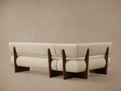 Beau Banquette corner in cream boucle upholstery, with a dark oak wood frame visible. Close-up shows soft texture.