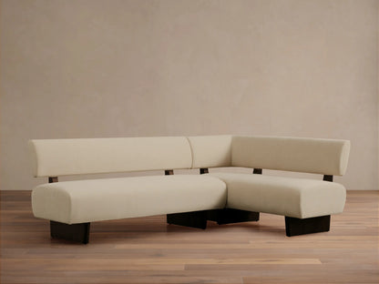Beau Banquette, L-shaped, cream upholstery, and dark exposed wood frame, on a wooden floor.