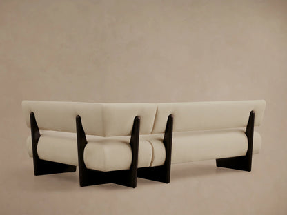 Beau Banquette, angled close-up. Light cream upholstery, dark brown exposed wood frame, showing modern curved lines.