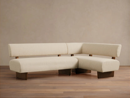 L-shaped Beau Banquette, cream boucle upholstery, low backrests, dark wood base, on a wooden floor against a neutral wall.