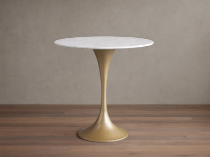 Round Saint Germain Bistro Table with a white Carrara marble tabletop and gold steel pedestal base on a wood floor background.