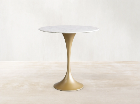 Round Saint Germain Bistro Table with a white Carrara marble tabletop and gold steel pedestal base on a wood floor background.