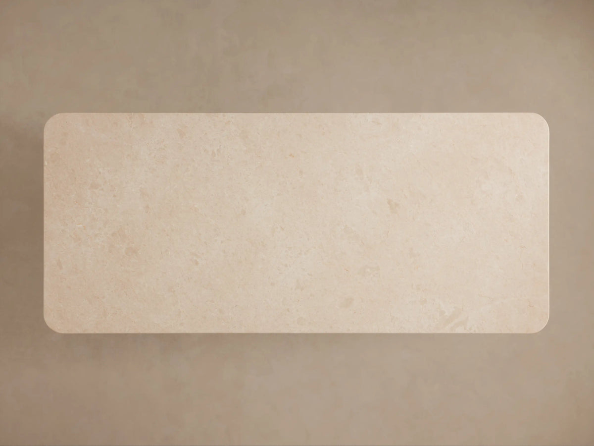 Close-up of Caden Dining Table's sand-colored stone top with rounded double-edge detail and light oak veneer base.
